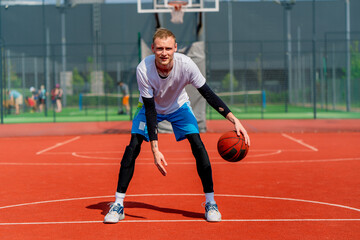 Obraz premium a Tall guy basketball player with the ball shows his dribbling skills during practice on the basketball court in the park 