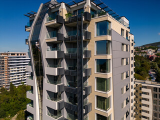 Industrial climber performs tasks at a great height on a glass wall of a tall building.