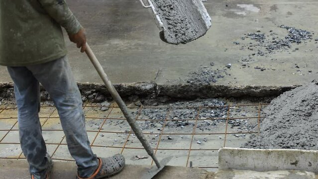 Concrete truck chute pouring wet cement mix into a form with reinforcing bar for a sidewalk.