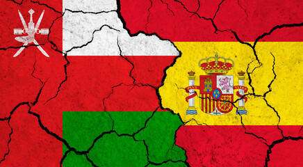Flags of Oman and Spain on cracked surface - politics, relationship concept