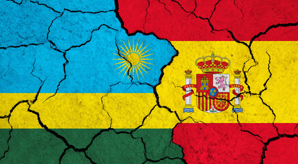 Flags of Rwanda and Spain on cracked surface - politics, relationship concept