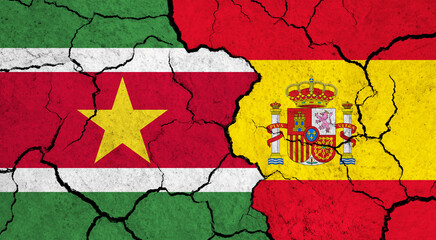 Flags of Suriname and Spain on cracked surface - politics, relationship concept