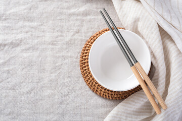 White bowl with chopsticks and linen napkin on kitchen table