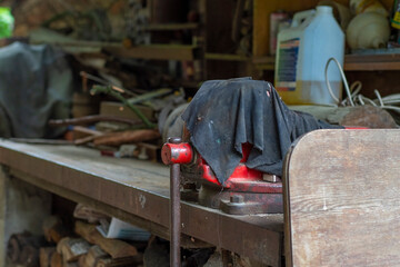 Abandoned workshop on the street under a canopy. Old table vise covered with rags.