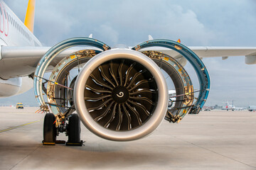 Jet engine. A modern, new generation, jet-powered passenger aircraft is waiting at the airport. Aircraft parked with open hatches for jet engine maintenance. - obrazy, fototapety, plakaty