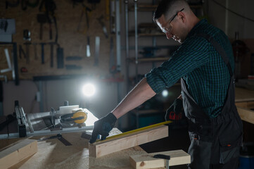 Carpenter measures a wooden board while working in a workshop. 