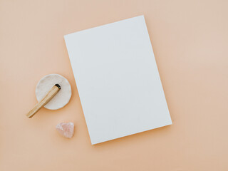 Empty blank white magazine cover mock up, pink crystal and palo santo on beige background.