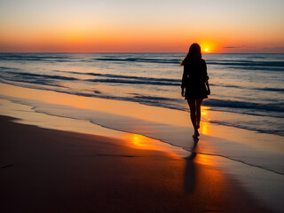 Frau spaziert im Sonneuntergang am Strand