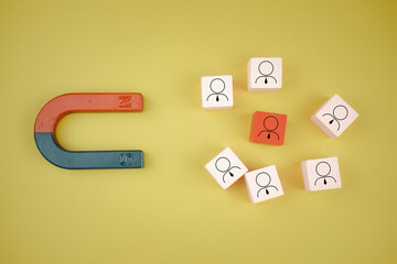 The magnet selects one red wood with human icons from many pink wood block human icons. Human...