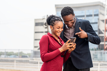 two young african business people checking a phone together