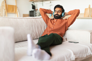 Middle Eastern man resting with headphones enjoying favorite music indoor - Powered by Adobe