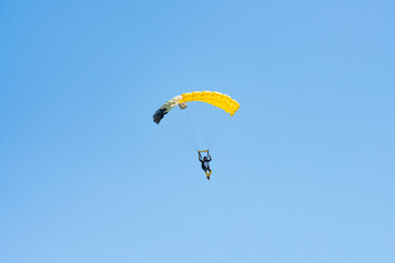 Stunning view of of a skydiver with a yellow parachute and a blue sky in the background.