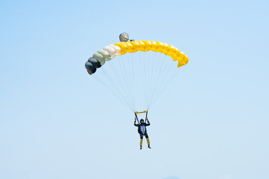 Stunning view of of a skydiver with a yellow parachute and a blue sky in the background.