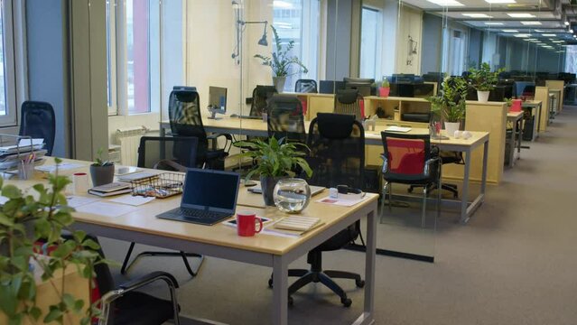 No people zoom in medium shot of empty workplace in open space office with laptop and stationery on desk