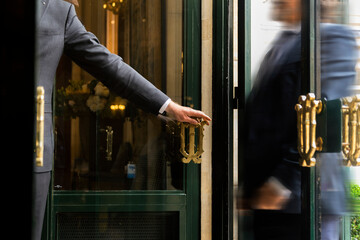Luxury service gesture – Business man holding a door handle with blurred motion of a guest...