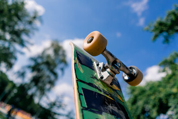 Close-up of a skateboard that a skateboarder is holding in his hand in the air against the background sky  © Guys Who Shoot