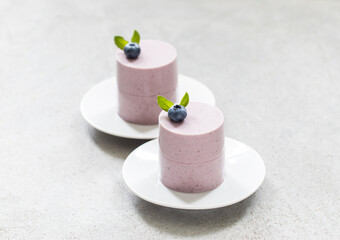 Modern dessert. Blueberry Panna Cotta cylindrical shape, on a plate. Light gray background. Close-up