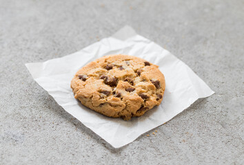 Vegan Round cookie with pieces of milk chocolate, on paper. Light grey background. Close up