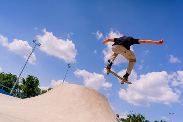 A young guy skater does a stunt on the edge of a skatepool against a backdrop of sky and clouds at a city skate park  © Guys Who Shoot