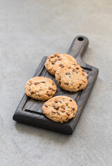 Vegan Round cookies with pieces of milk chocolate, on a wooden board. Light grey background. Rustic style