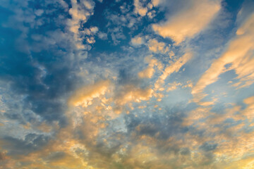 Blue sky with clouds at sunset. Colorful cloudy landscape illuminated by the evening sun. Abstract background.