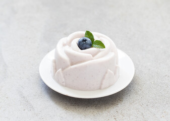Blueberry cream dessert, Panna Cotta, in the shape of a rose, on a plate. Light grey background