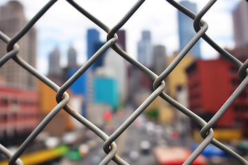 Through a chain-link fence, you can glimpse a view of the city.