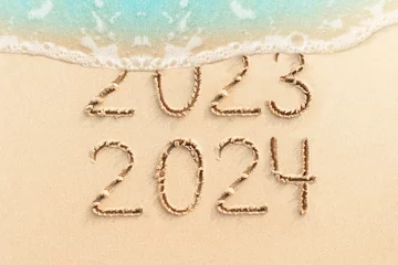 Foto op Aluminium New Year 2024 concept photo. Numbers 2023 written on sandy beach with blue ocean wave on background.  © Oleandra9