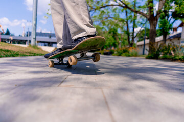 Close-up of a young boy doing a skateboarding trick on the path of a city park against the background of trees