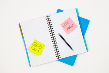 Notebooks, paper reminders and pen on a white background, top view.