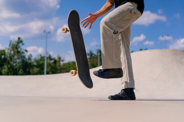 Close-up A young skateboarder guy tosses a skateboard with his hands and tries to do a stunt in a...