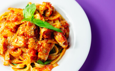 Cooked cellentani pasta with cooked chicken breast and peppers in a spicy tomato and jalapeno dressing