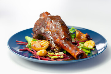 Delicious Lamb shank with red wine and rosemary gravy served on the mixed leaf salad, on the blue plate