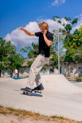 Young guy skateboarder with long hair skateboarding in the city a skatepark and talking on the phone 