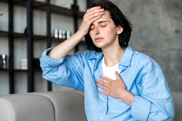 Woman sitting on sofa and having asthma or panic attack
