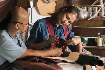 Young leather making woman working with genuine leather with leather maker man teacher in workplace