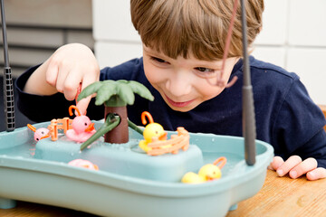 Child playing with pool of water toys and catches ducks. Free time at home, soothing activities for children. Children's activities, easy ideas for children at home. Art lessons at home.