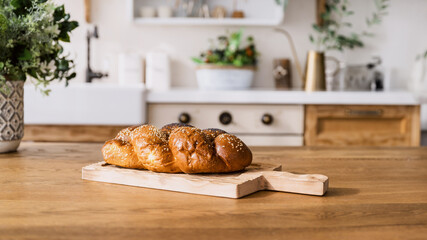 fresh baked bread or bun with sesame seeds on wooden cutting board