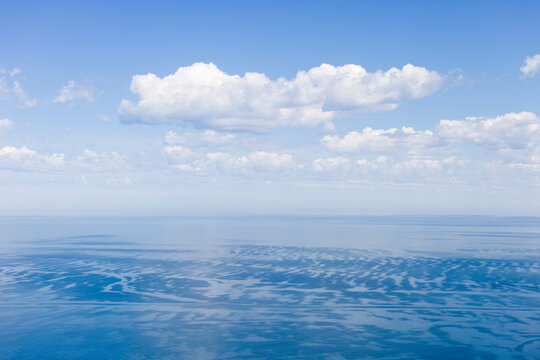Aerial view of the blue ocean water surface with scattered clouds in the sky, Melbourne, Victoria, Australia.