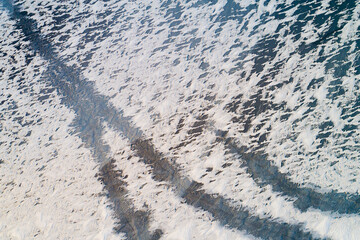 Abstract aerial view of snow remains with gaps on the ice of a frozen lake in winter, Reykjanes, Iceland.