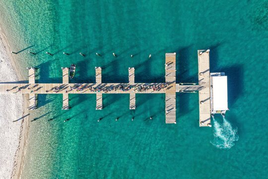 Aerial view of a boating dock surrounded by clear blue waters, with people waiting to get on the boat on Peanut Island Park near Riviera Beach, Florida, United States.