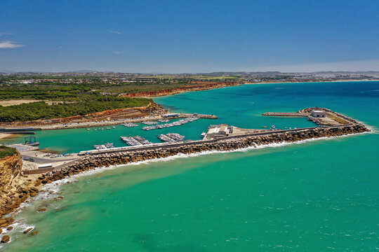 Aerial view of the marina Muelle Pesquero de Conil surrounded by turquoise waters on a clear sunny day in the town of Conil de la Frontera off the coast of C&aacute;diz, Andalusia, Spain.