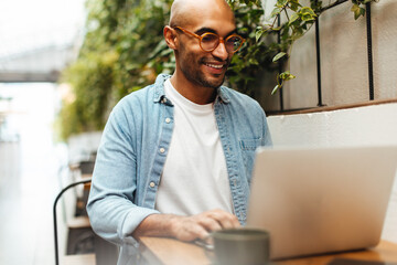 Working from anywhere: Freelancing man using his laptop in a coworking space - obrazy, fototapety, plakaty