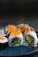 Vertical closeup shot of assorted sushi rolls on a blue plafe