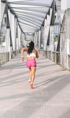 Young female in sporty clothes running in street