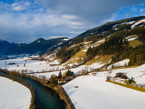 Aerial drone view of the Ziller river in the Ziller valley covered in snow on a cloudy day located in the Austrian alps in winter, Fuegen, Tyrol, Austria.