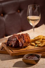 Cozy outdoor dining setup with savory meat, fries and a glass of wine