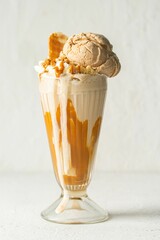 Glass of a creamy orange milkshake topped with ice cream