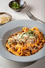 Bowl of delicious fresh pasta with meat, sauce, and cheese on the table