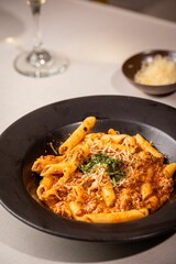 Bowl of delicious penne pasta with cheese and sauce on the table